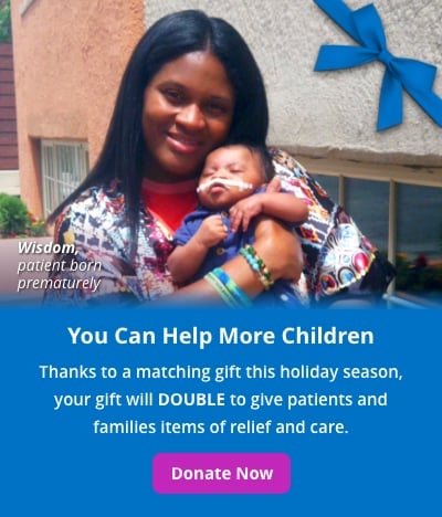 A Black woman holds a newborn baby boy, Wisdom. Text reads: You can help more children. Thanks to a matching gift this holiday season, your gift will DOUBLE to give patients and families items of relief and care. Donate now.