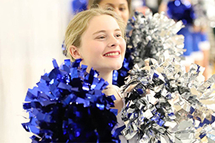 Bobbi Horr smiling and holding blue and sliver pom-poms