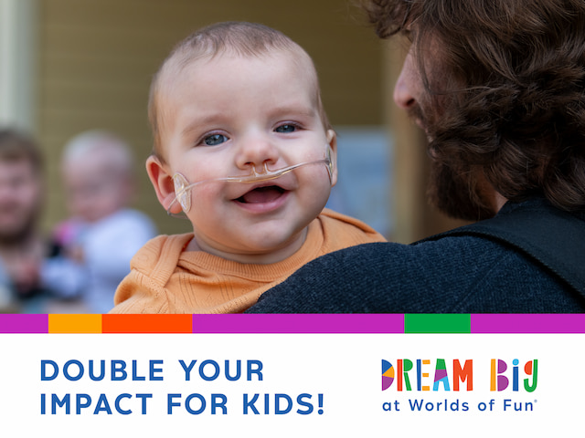 Promotional graphic showing a young child being held by an adult. The child is wearing a nasal cannula. Text at the bottom reads, “DOUBLE YOUR IMPACT FOR KIDS!” alongside the Dream Big at Worlds of Fun logo. Colorful accent bars appear above the text.