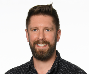 schuetz-nikolaus headshot with black button up and pattern